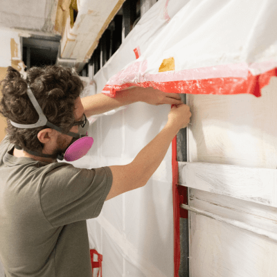 Man Wearing Respirator Inspects Home Construction Site after Mold Remediation